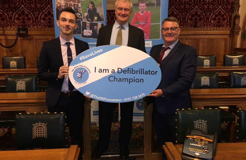 Graham holding an OK Foundation Sign, reading "I am a Defibrillator Champion"