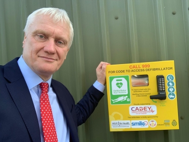 Graham standing next to an Automated External Defibrillator